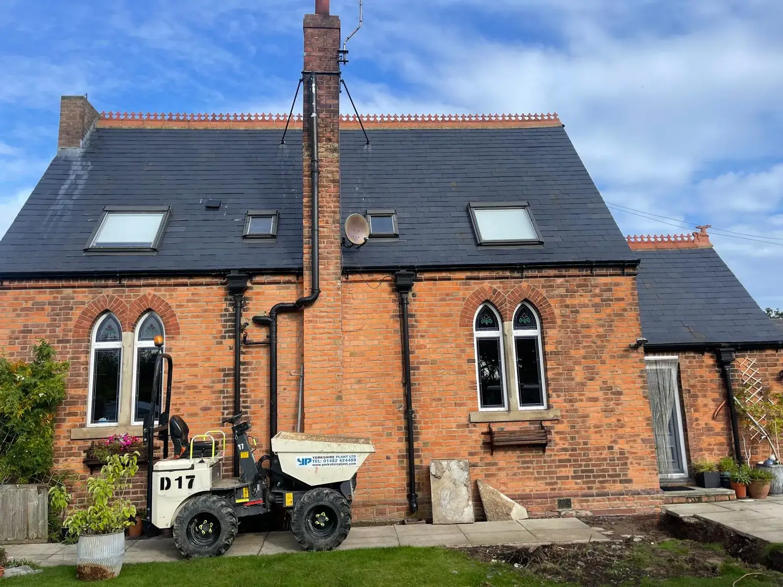 A tractor parked in front of a brick house.
