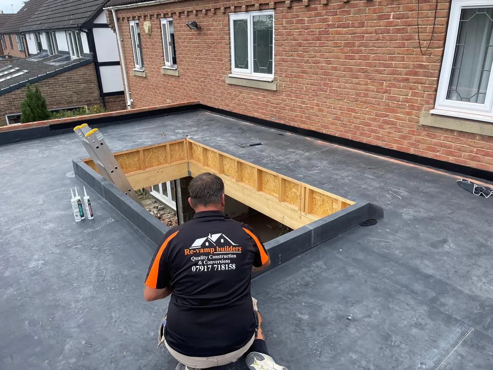 A man working on a flat roof in a residential area.
